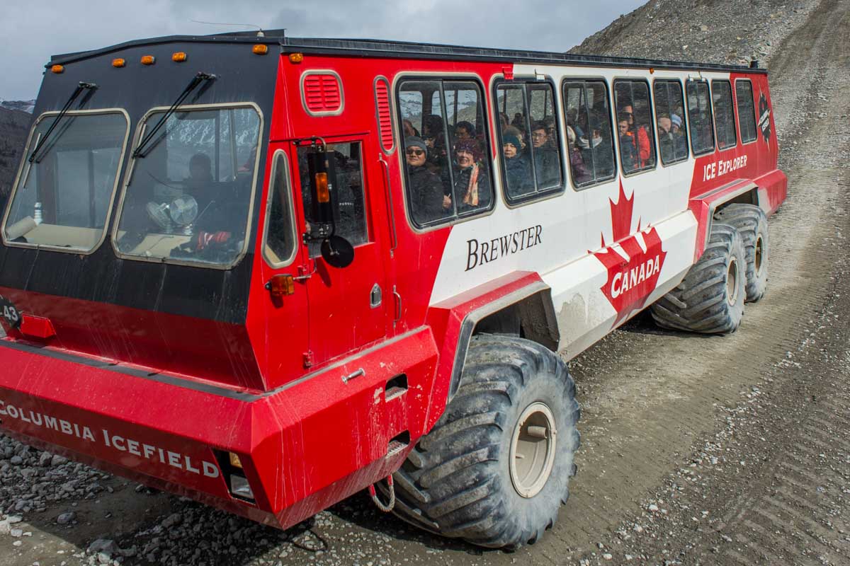 A red Ice Explorer all-terrain vehicle travels down a steep hill on the way to the Athabasca Glacier in the Columbia Icefield, Canada