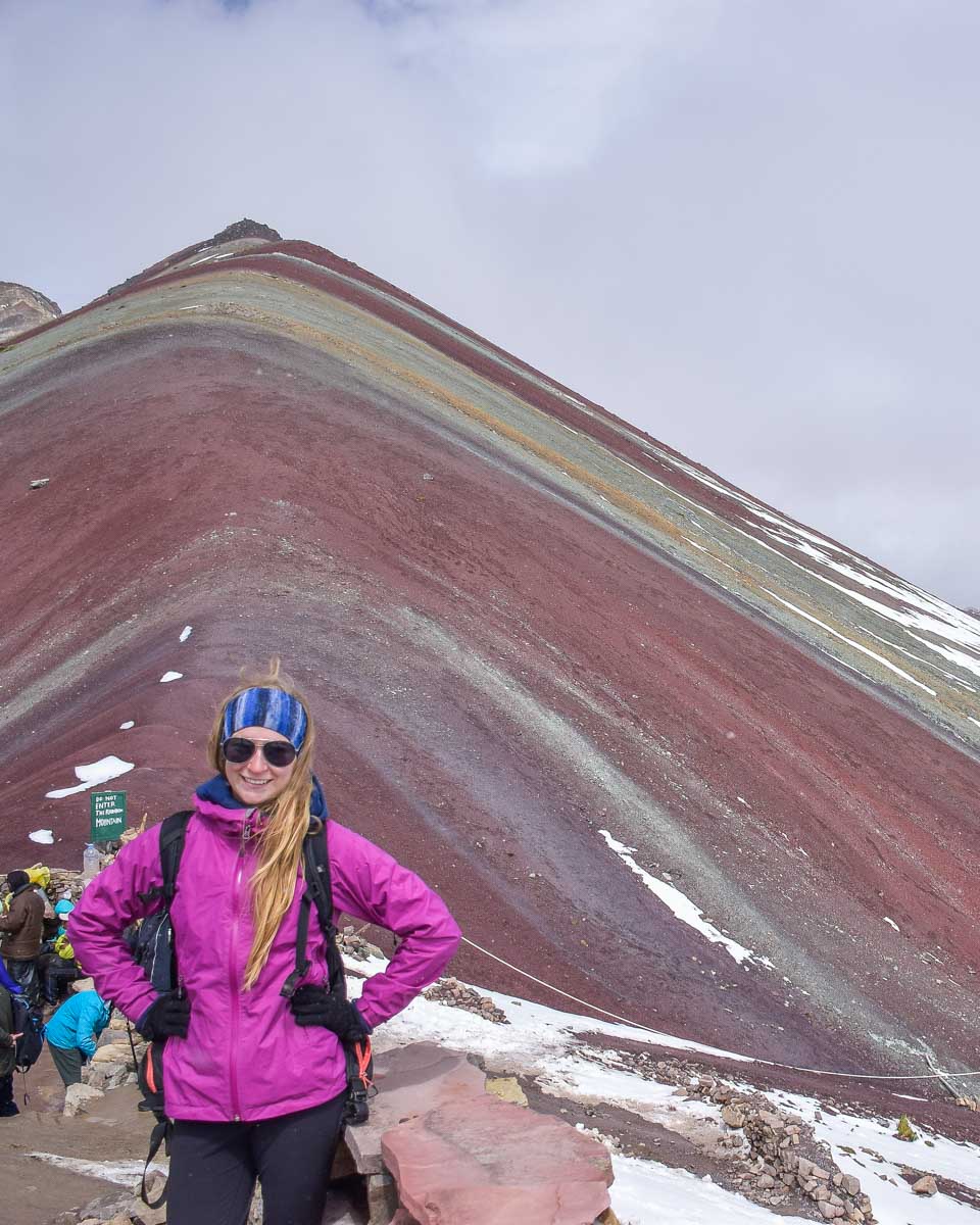 Bailey takes a photo with Rainbow Mountain in the background