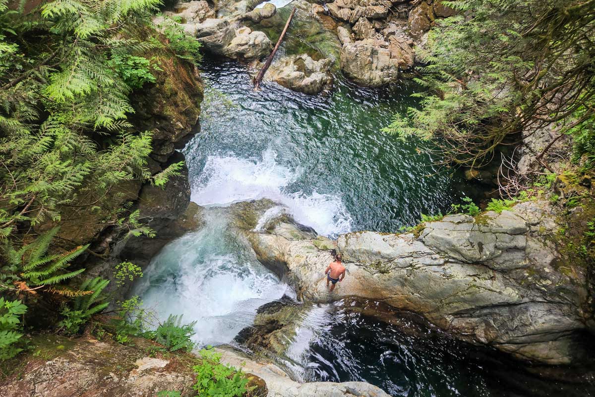 A man prepares to jump into the water in Lynn Canyon from a cliff
