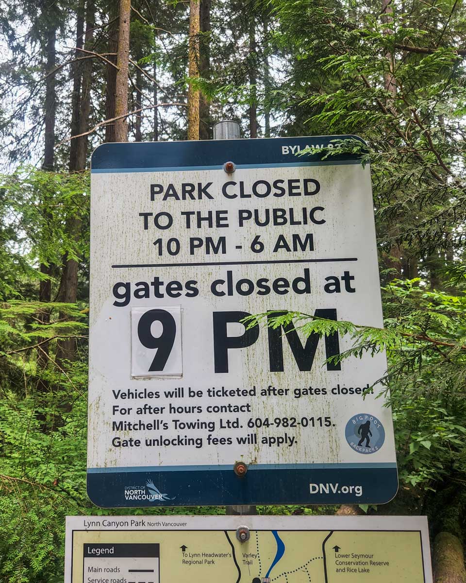 A sign showing the hours of the park in Lynn Canyon
