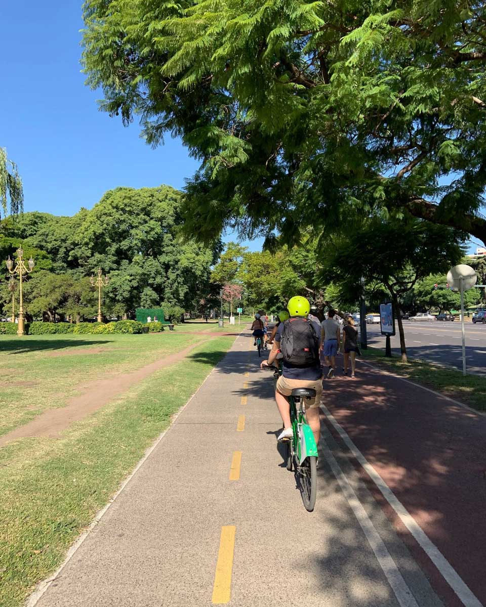 People bike next to a park on a BA Bikes in Buenos Aires