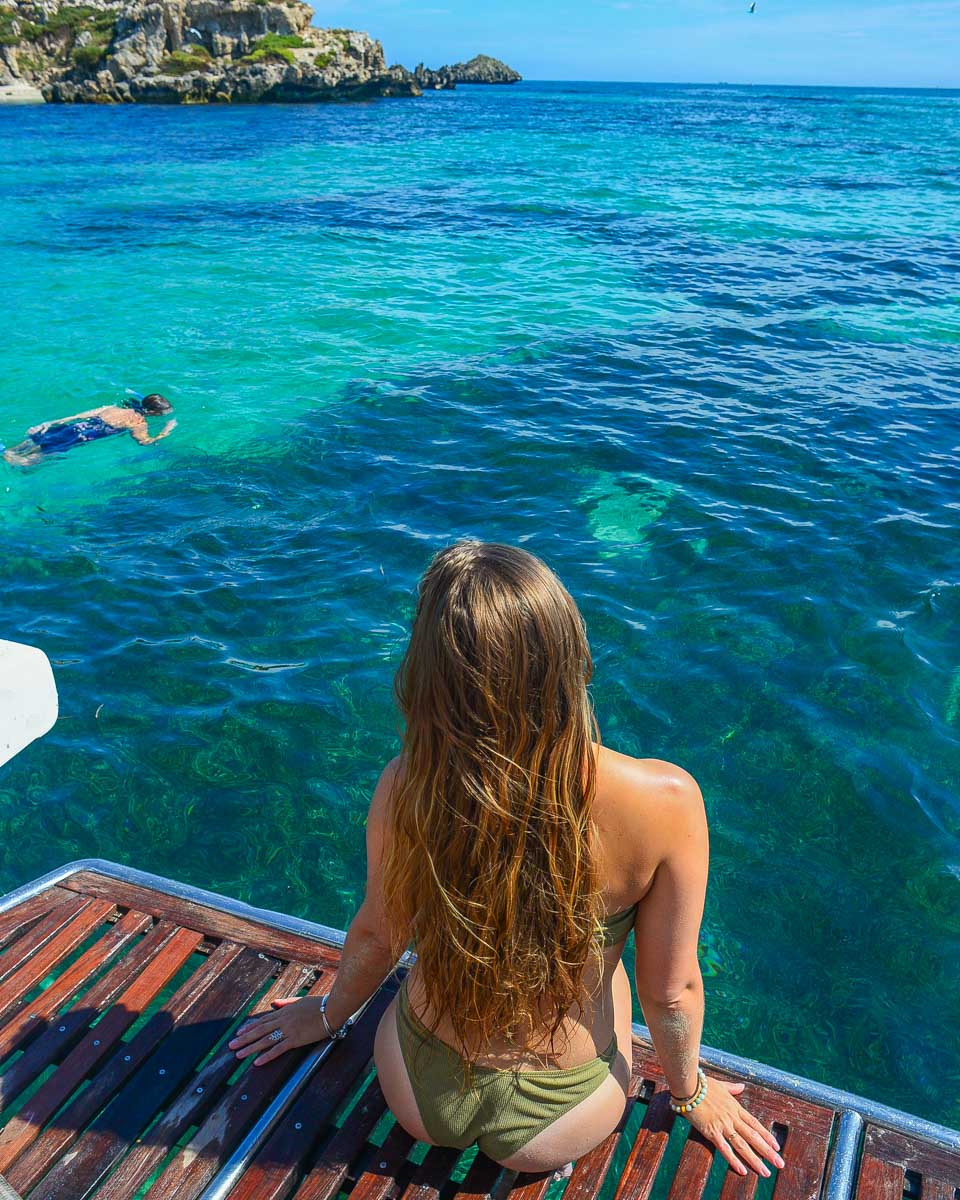 Bailey sits on the edge of the boat on a tour to Carnac Island, Perth