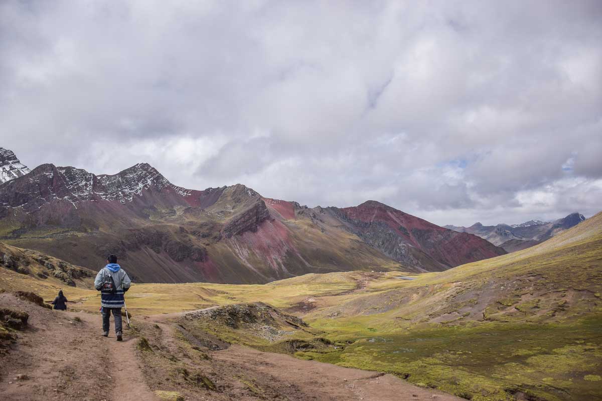 A man walks on a trail at the start of Rainbow Mountain