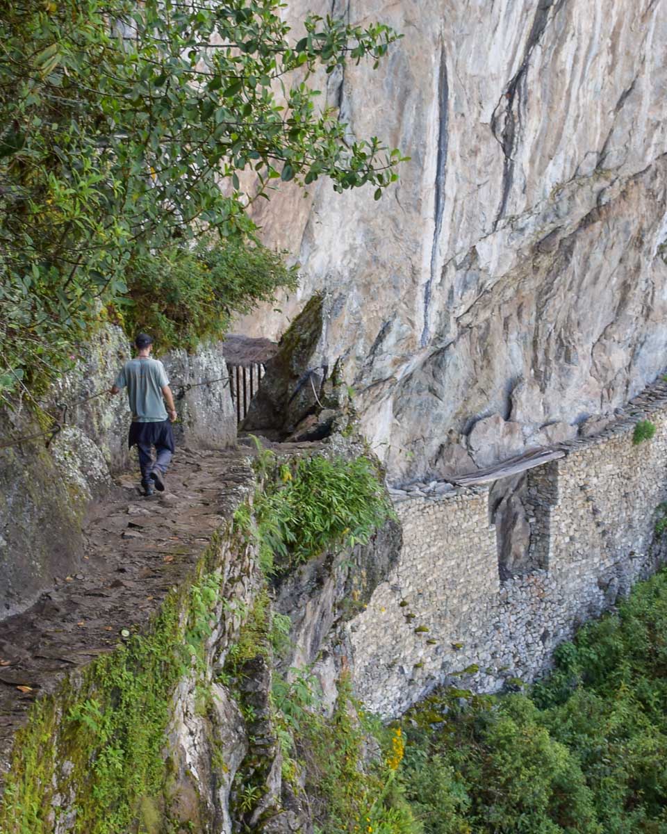 A man walks towards the Inca Bridge at Machu Picchu, Peru
