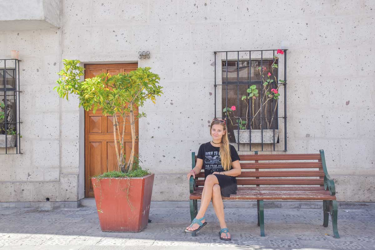 Bailey sits on a bench in front of a white building made from volcanic rock in Arequipa, Peru