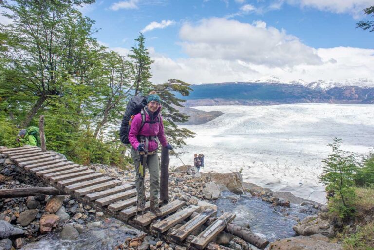Bailey walks across a bridge in Torres del Paine National Park with Glacier Grey in the background