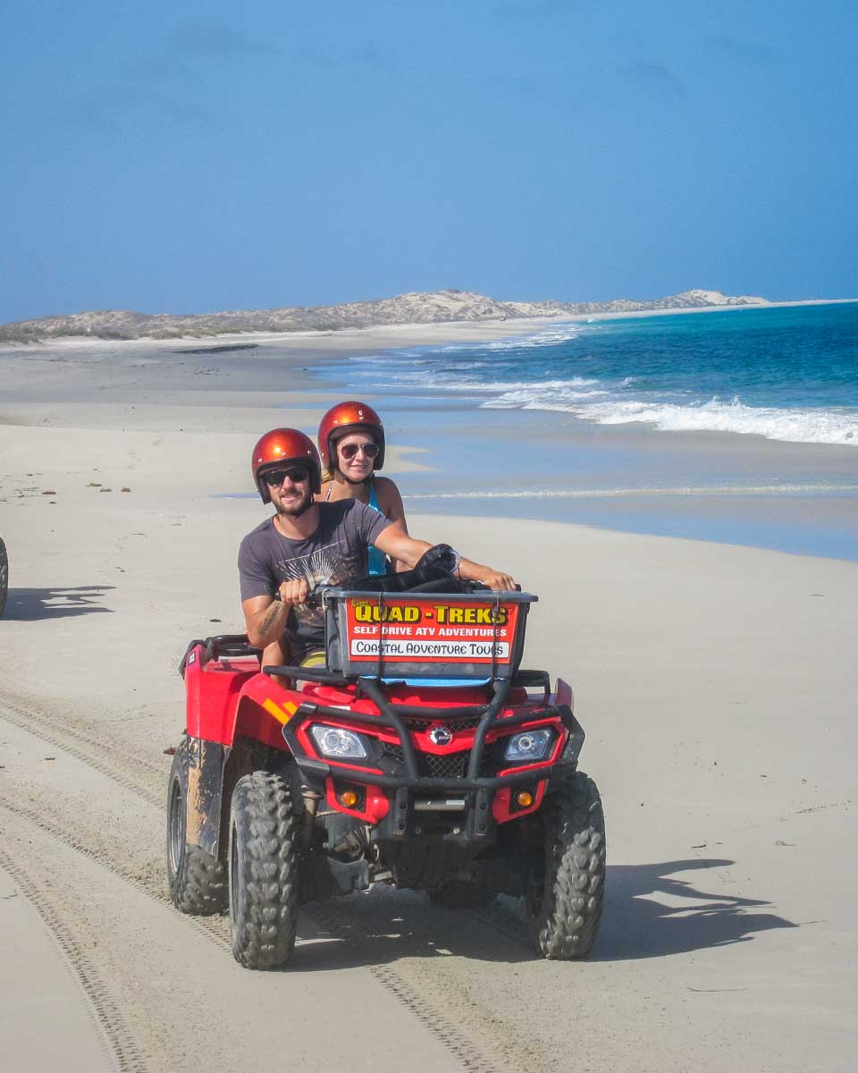 Daniel and Bailey ride an ATV along the beach in Coral Bay, Western Australia