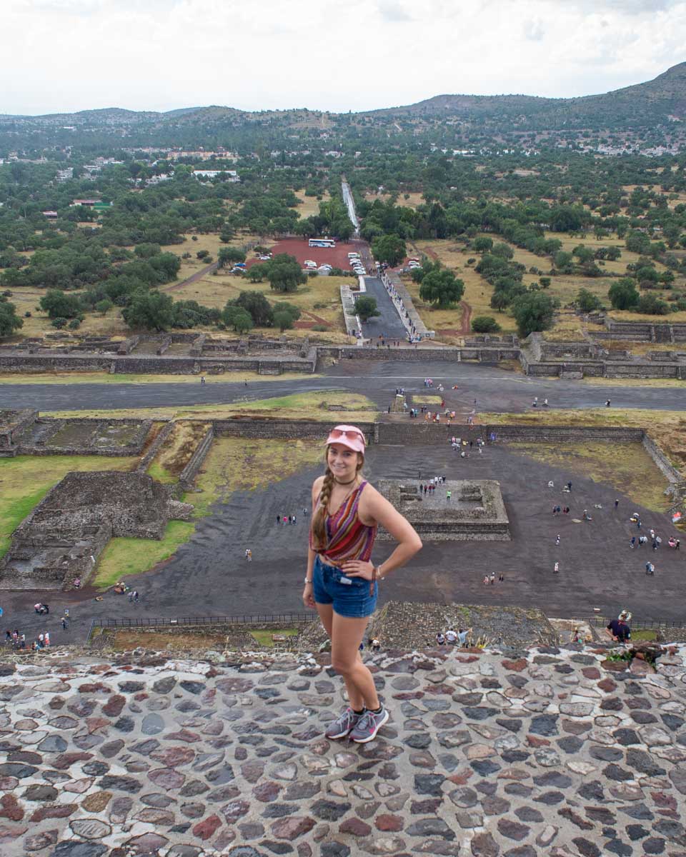 A lady stands at the top of The Pyramid of the Sun in Teotihuacan, Mexico