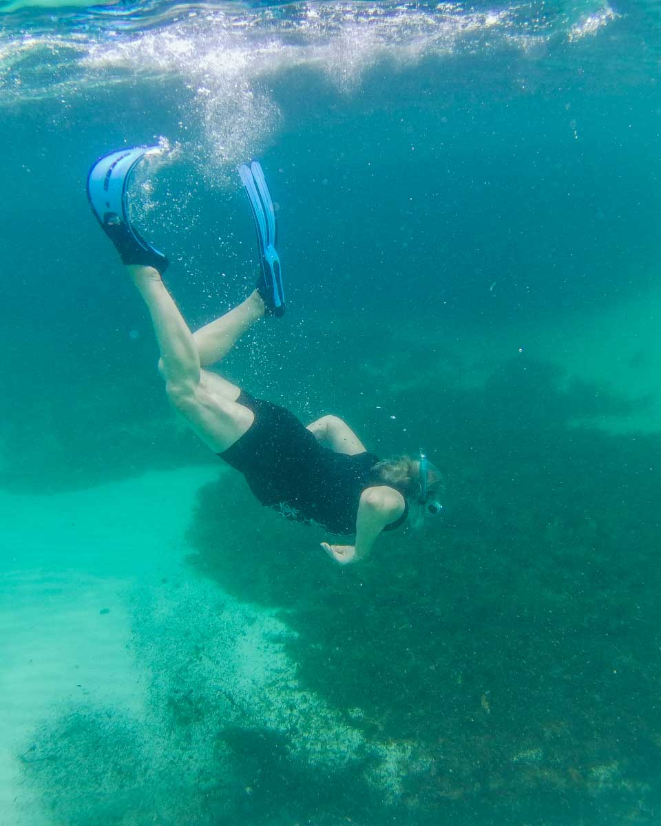 A lady dives down under the water at the Basin on Rottnest Island, Perth