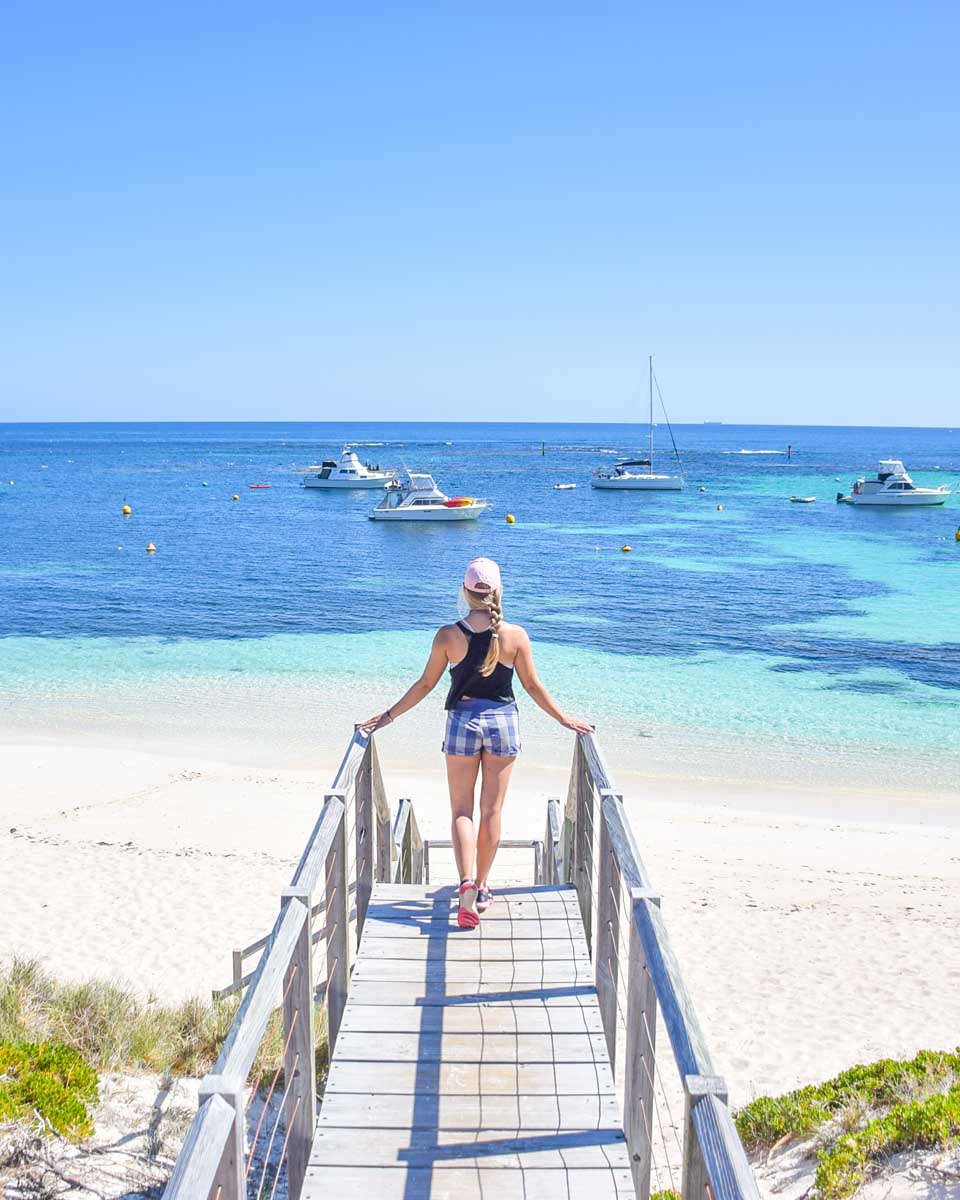 A lady stands on some steps at a stunning beach on Rottnest Island