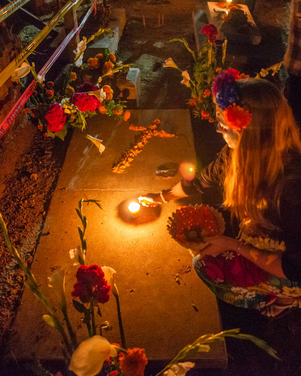 Bailey lights a candel on a grave during Day fo the Dead in Oaxaca, Mexico