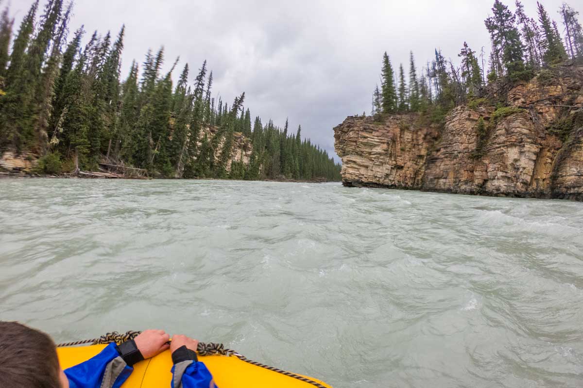 A kid hangs onto the front of a raft in Jasper