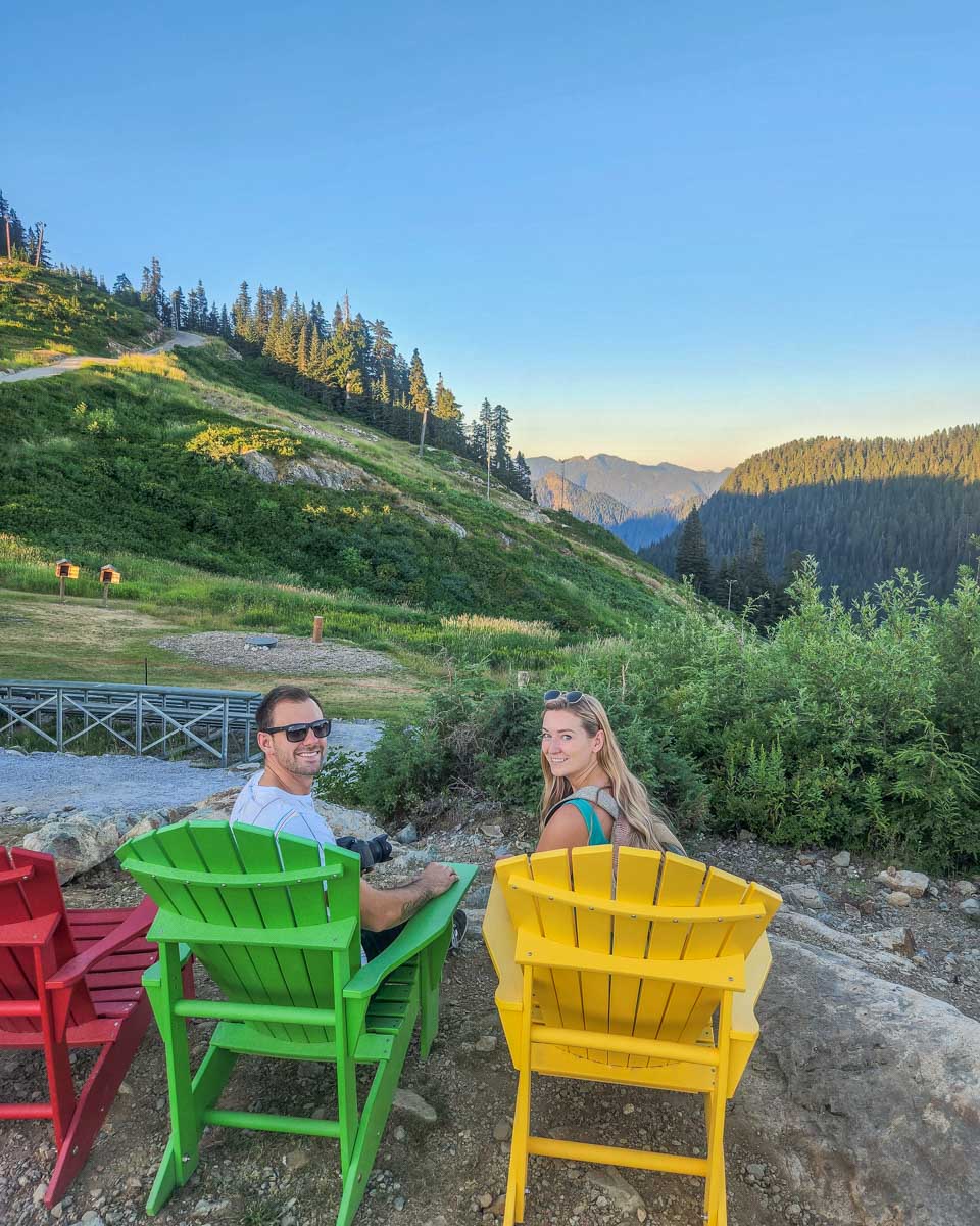 Bailey and Daniel sit in chairs with a view on Grouse Mountain, Vancouver
