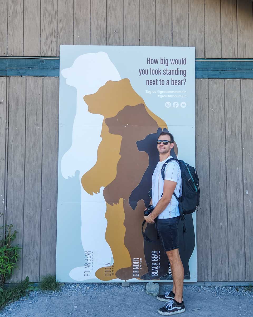 Daniel poses for a photo at a sign showing the size of each bear on Grouse Mountain, Vancouver
