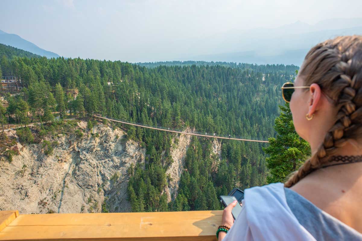girl with french braids looks over the edge of the golden suspension bridge in golden bc