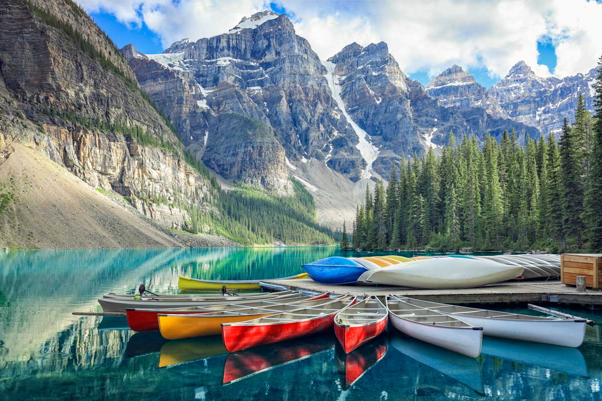 Canoes sit on the shoreline of Moraine Lake in Banff National Park