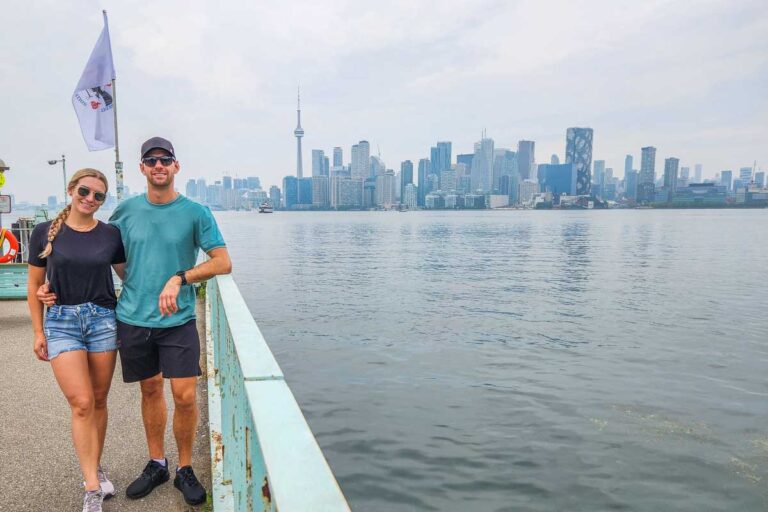 Bailey and Daniel pose for a photo at the ferry terminal on the Toronto Islands with a view of Torontos skyline in the background