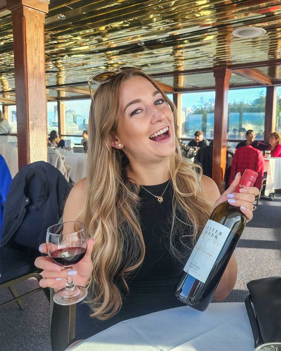 Bailey poses for a photo with a bottle of wine on a sunset cruise in Vancouver