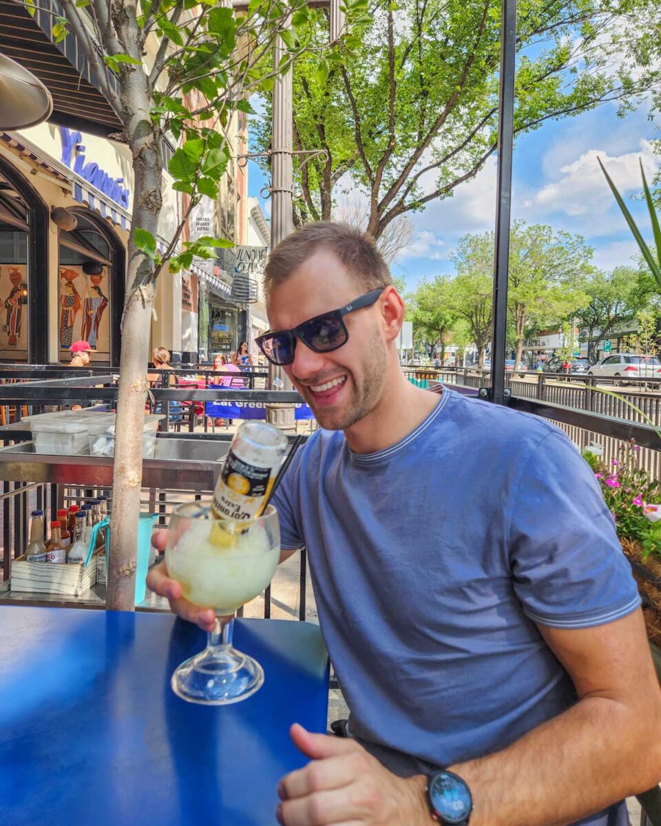 Daniel sits on a streetside patio at Julios Barrio restaurant on Whyte Ave with a huge margarita