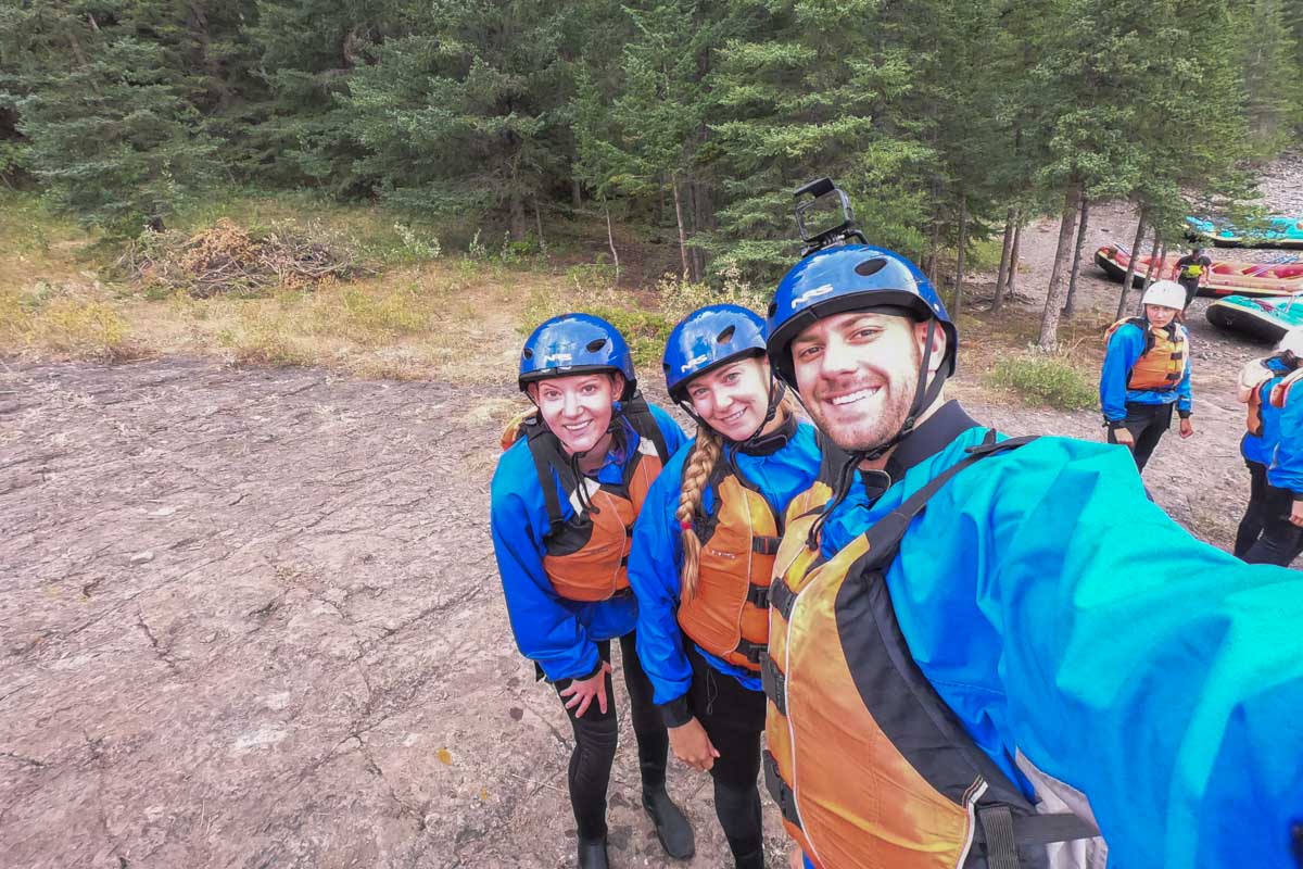Three people take a selfie while rafting in Banff