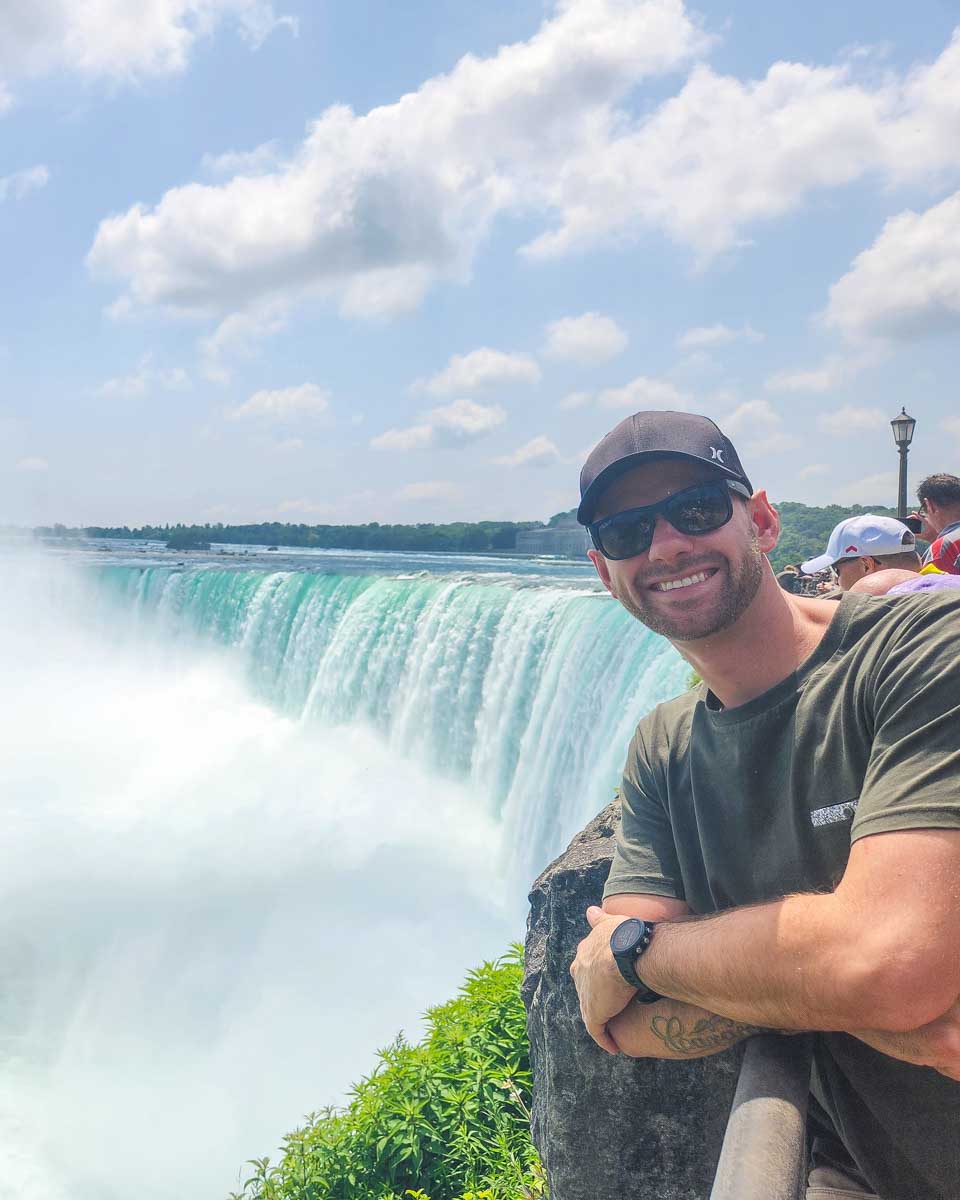 Daniel leans over the railing at Niagara falls and poses for a photo on the Canadian side