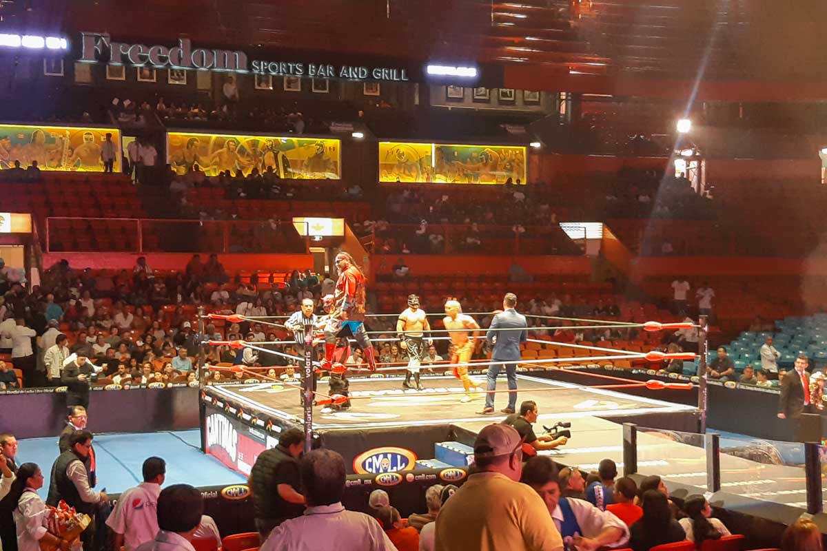 A lucha libre wrestler stands on the ropes during a show in Mexico City