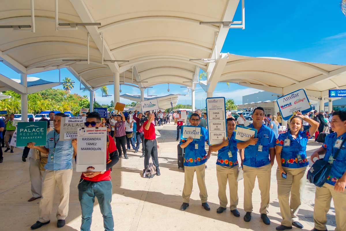 Group of shuttle works hold oup signs with peoples names outside Cancun Airport, Mexico