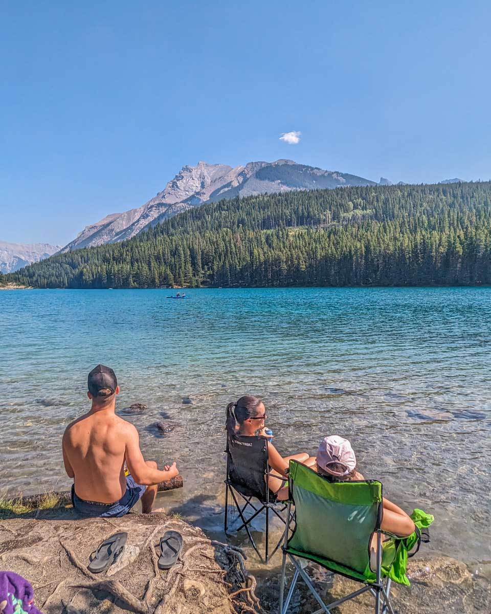 Three people relax at two Jack Lake on a hot summers day in Banff National Park