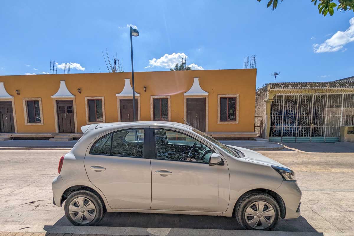 A small rental car is parked on the side of the road in Mexico