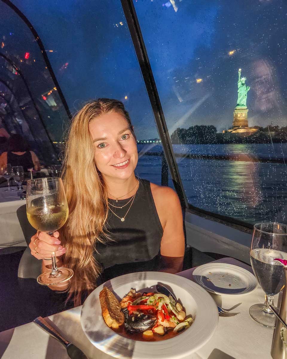 Bailey enjoys her dinner with the Statue of Liberty in the background during the Bateaux New York Premier Dinner Cruise in New York City