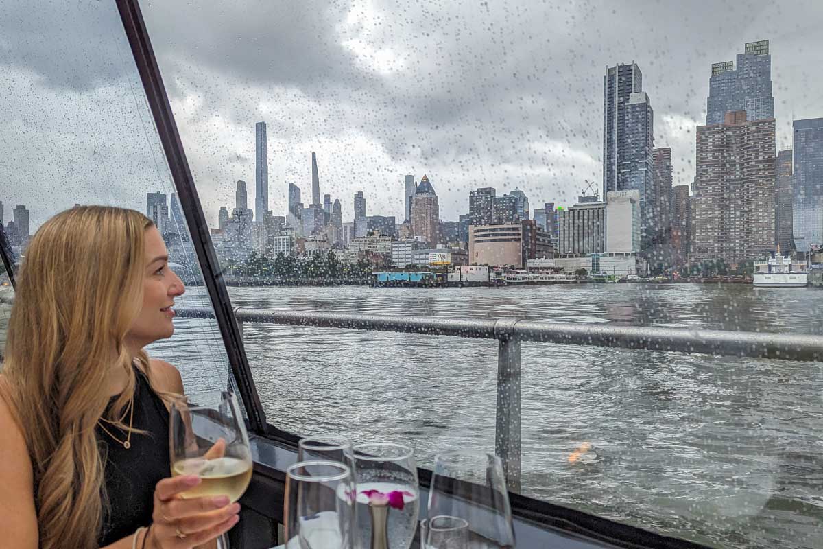 Bailey looks out the window on the Bateaux New York Premier Dinner Cruise with a glass of wine