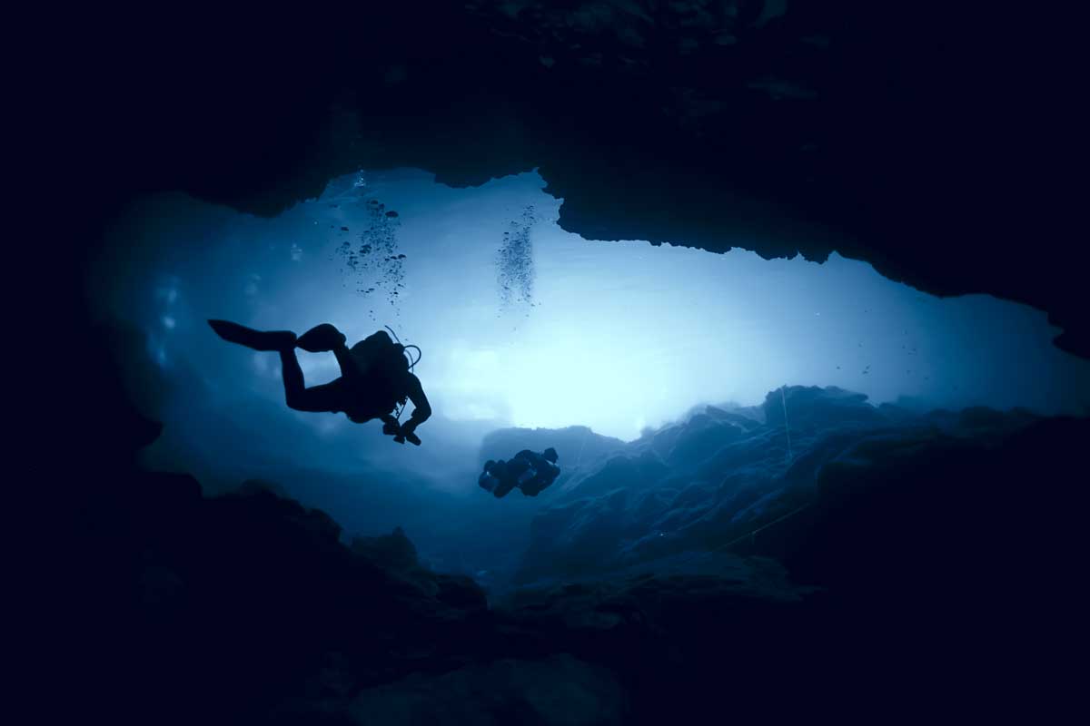 Scuba diving in dark cenote in Tulum, Mexico