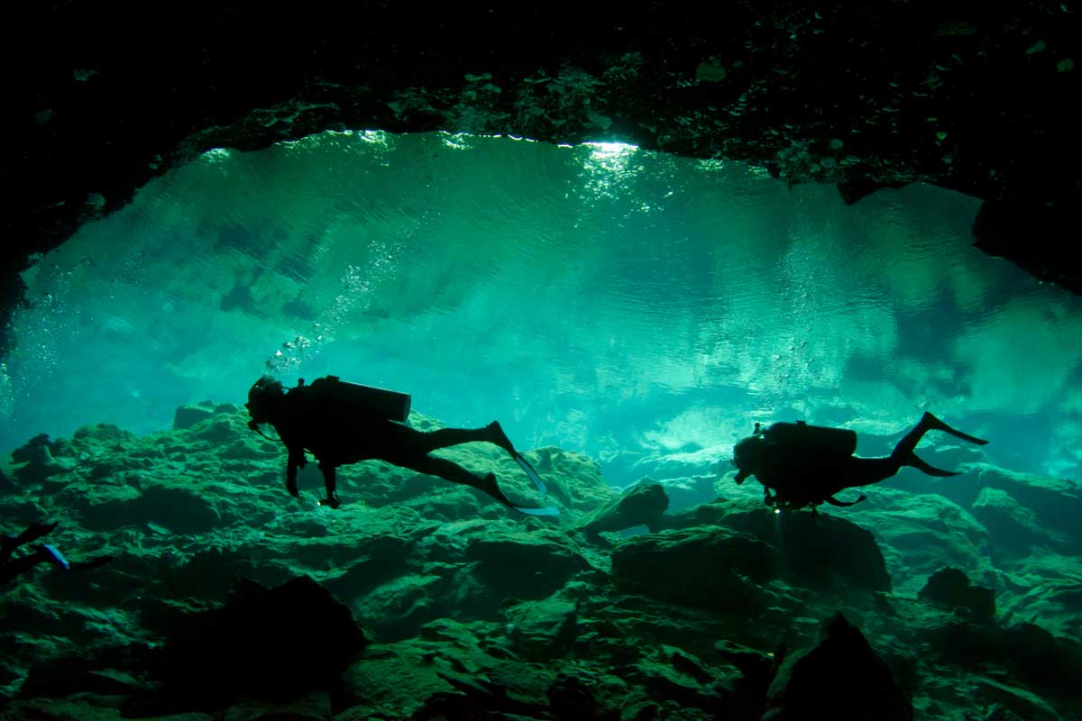 Two people dive in a cenote in Tulum, Mexico