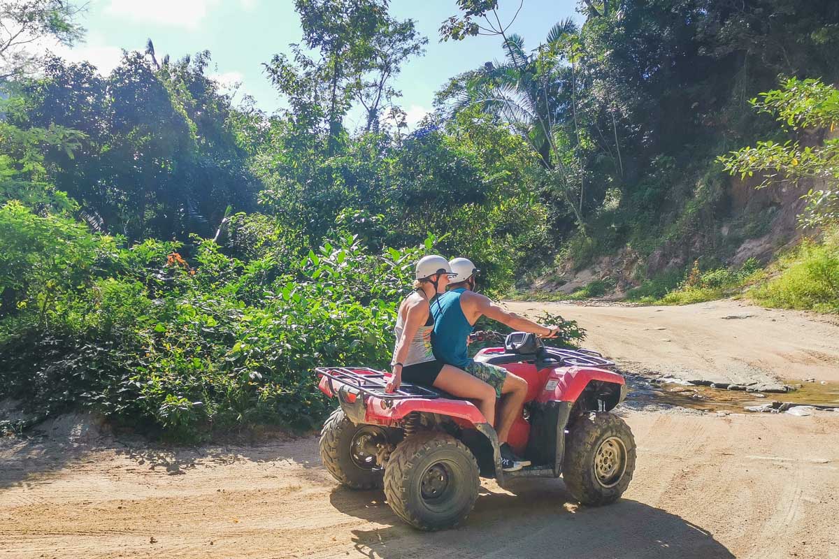 Two people ride an ATV around a corner in Mexico