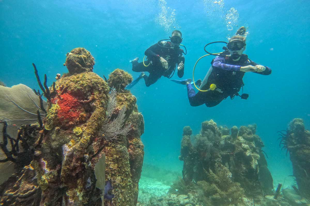 Two people scuba dive the MUSA Reef off the coast of Cancun, Mexico