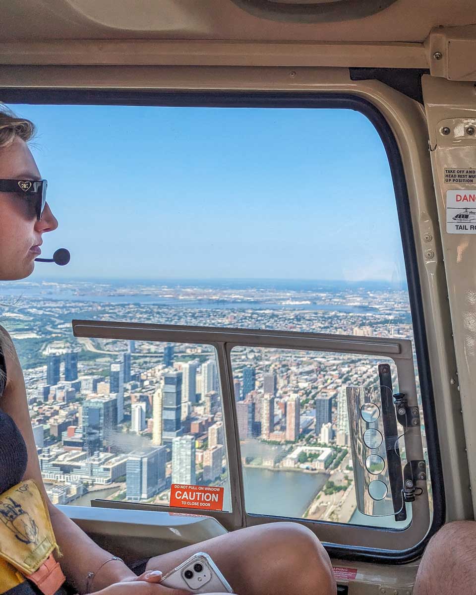 A lady looks out the window on a helicopter over New York City