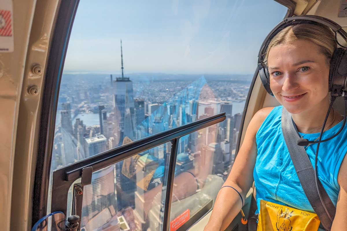 Bailey smiles at the camera with views of New York City in the background on a helicopter ride