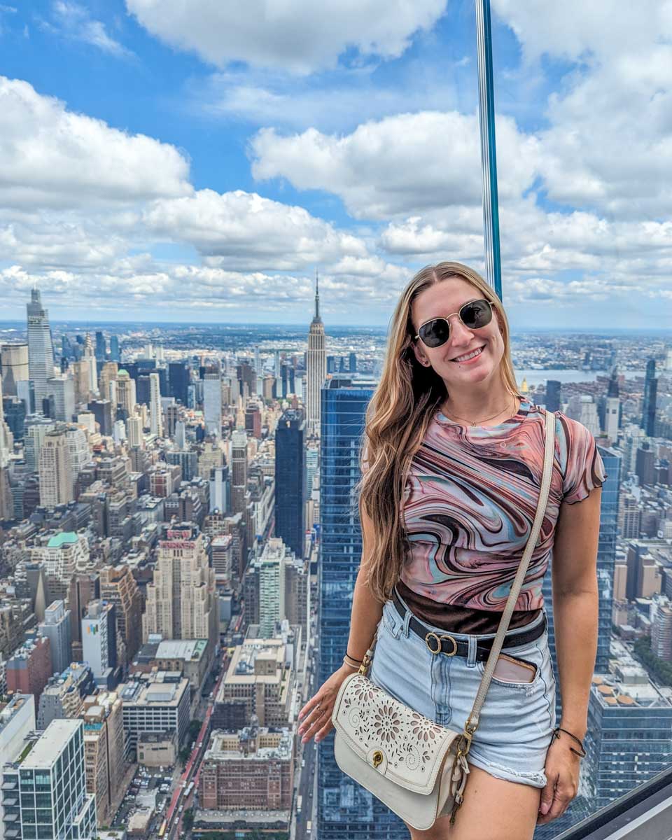 Bailey stands up against the glass wall with views of New York City at the Edge NYC