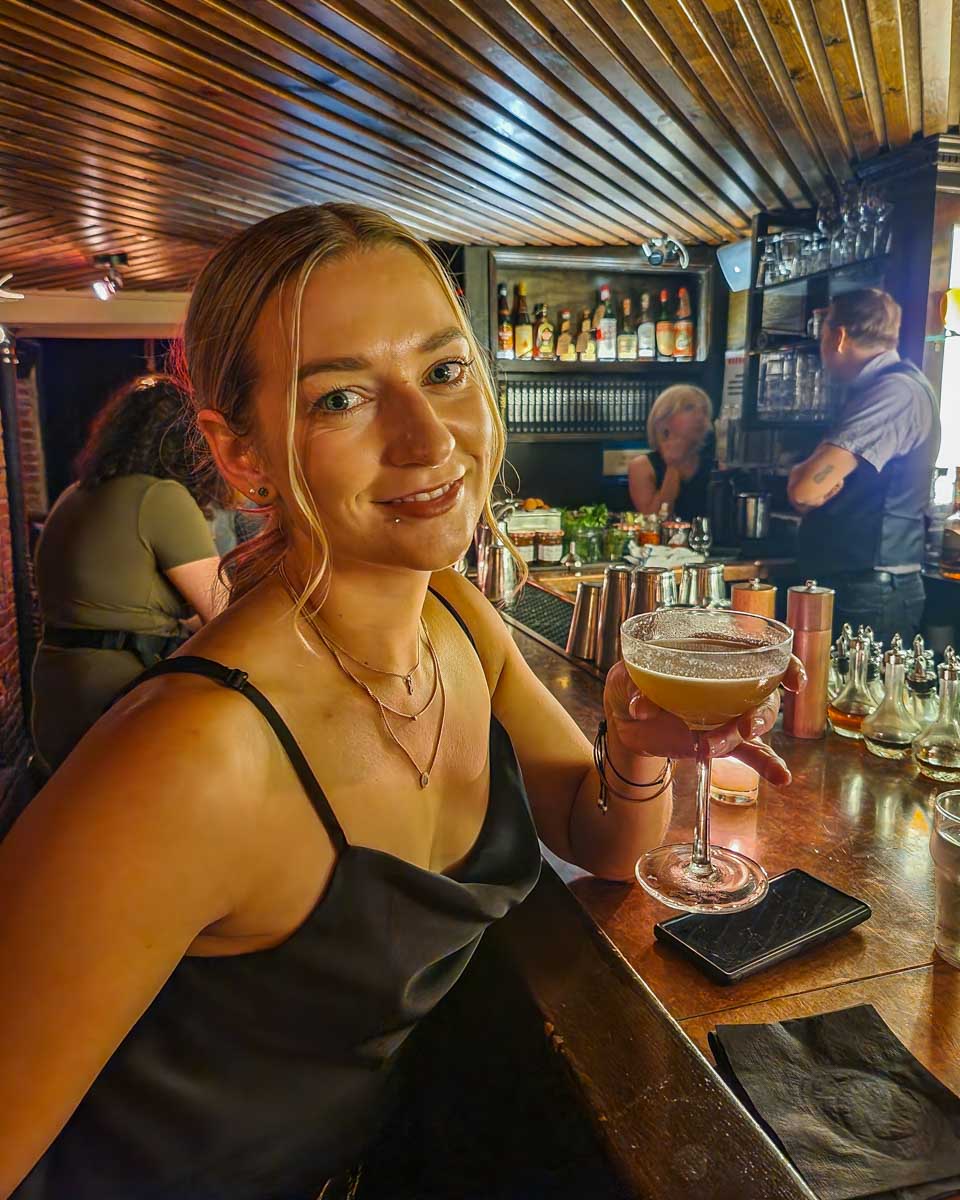 Bailey enjoys a cocktail at Please Don't Tell Speakeasy in New York City