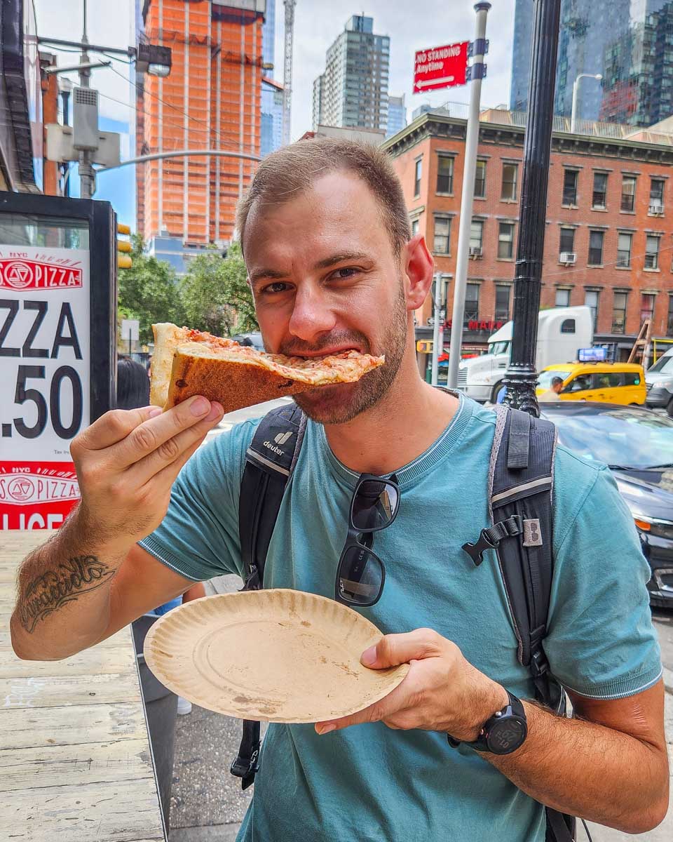 Daniel eats a slice of pizza on a food tour in New York City