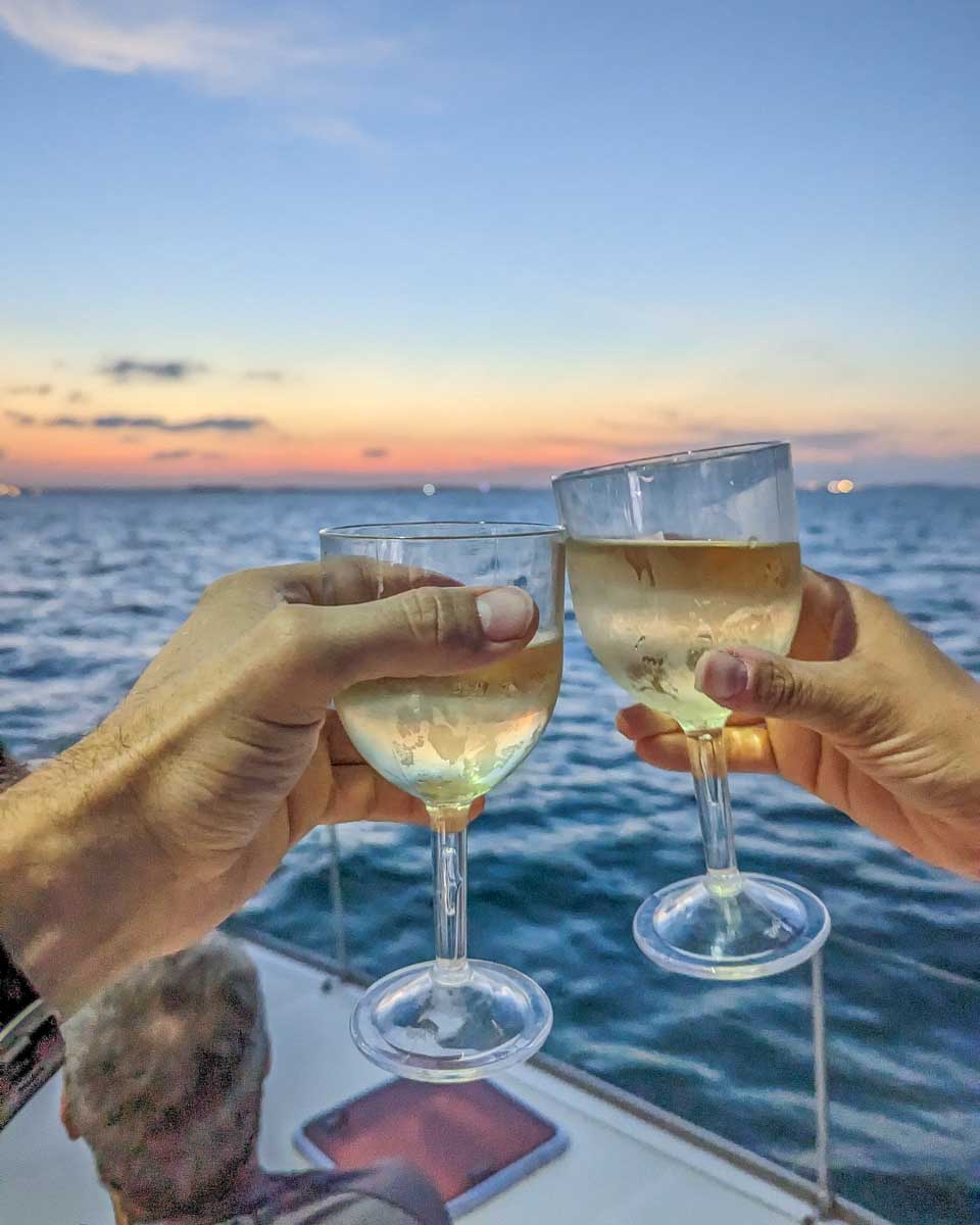 Bailey and Daniel cheers with wine at sunset on a catamaran cruise in Playa del Carmen, Mexico