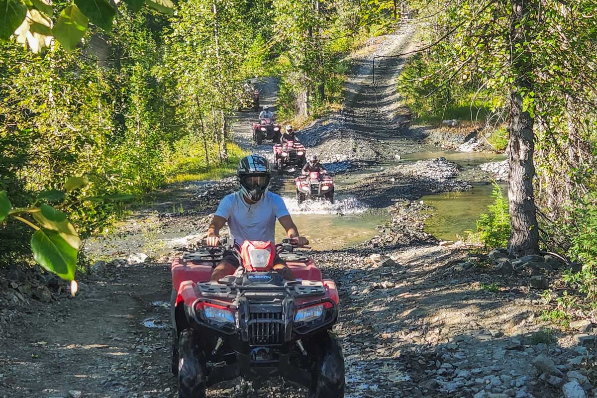 People ride an ATV through a puddle on a tour in Playa del Carmen, Mexico