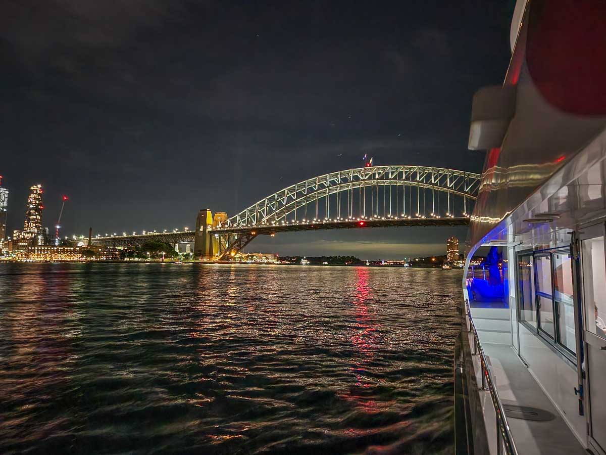 A boat cruises towards the Sydney Harbour Bridge on the Journey Beyond the Cruise Sydney