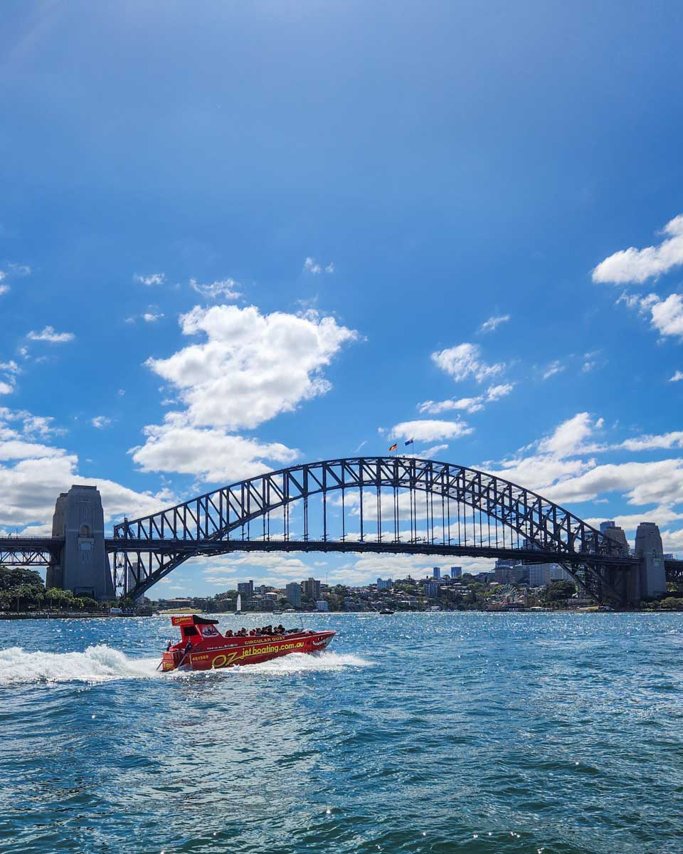 A jet boat travels beside the Sydney Harbour Bridge in Sydney, Australia on a tour