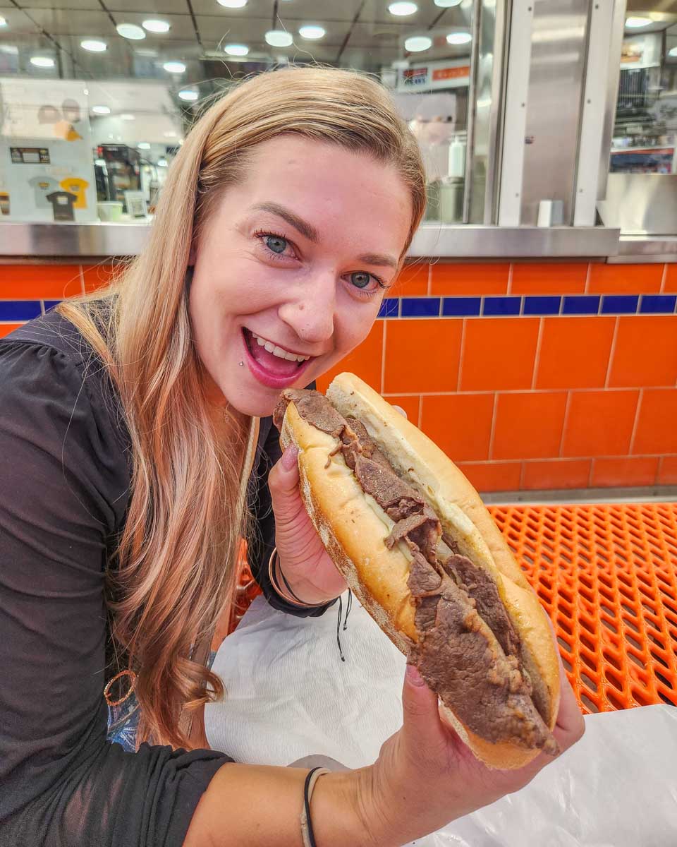 Bailey bites into a Philly Cheese Steak during a food tour in Philadelphia