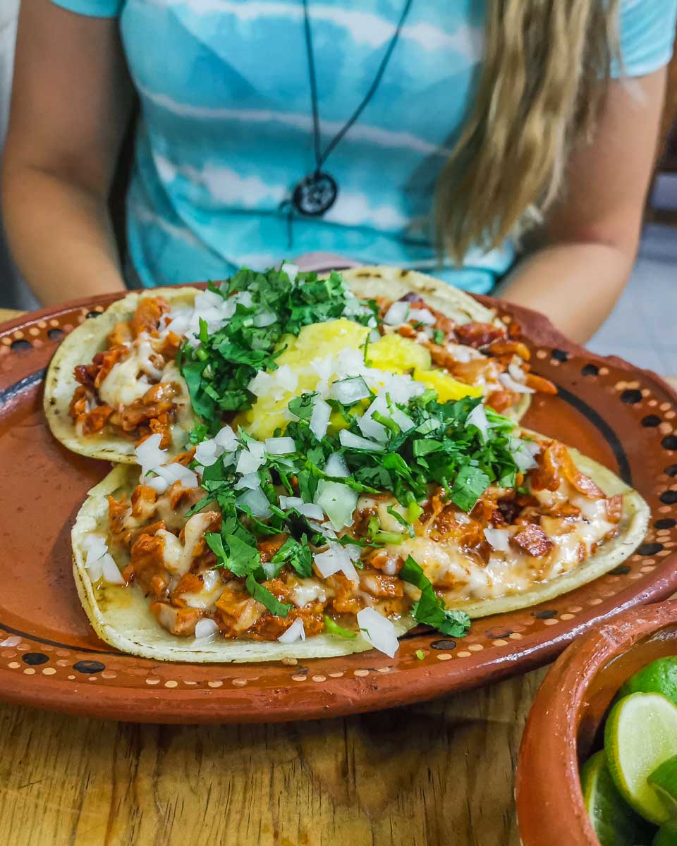 Bailey sites behind a huge plate of al pastor tacos on a taco tour in Cancun, Mexico