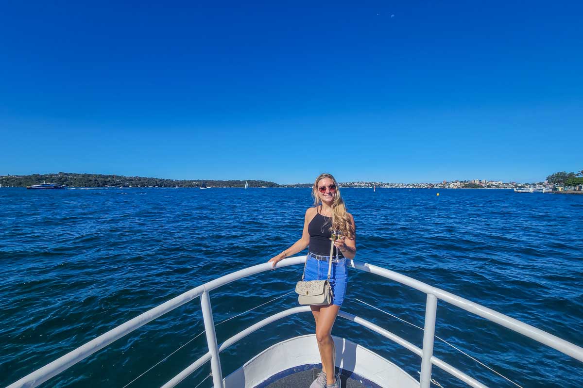 Bailey stands at the front of the boat during a Sydney Harbour Cruise and enjoys the sunshine and views