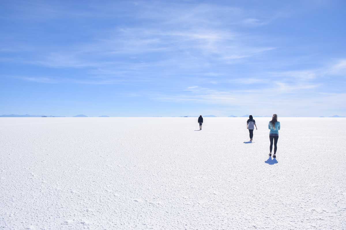A tour group walks along the Uyuni Salt Flat in Bolivia on a tour