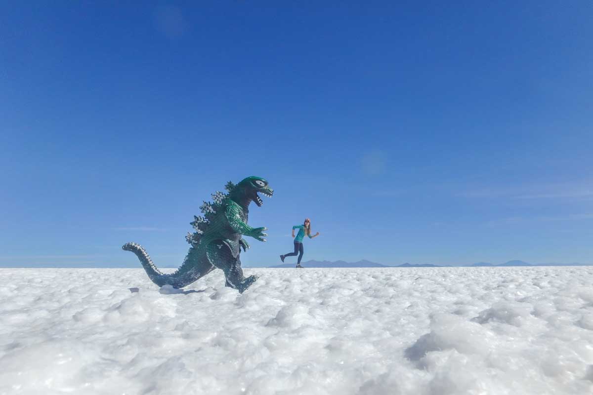 A toy Godzilla looks like it is chasing Bailey on the Uyuni Salt Flat
