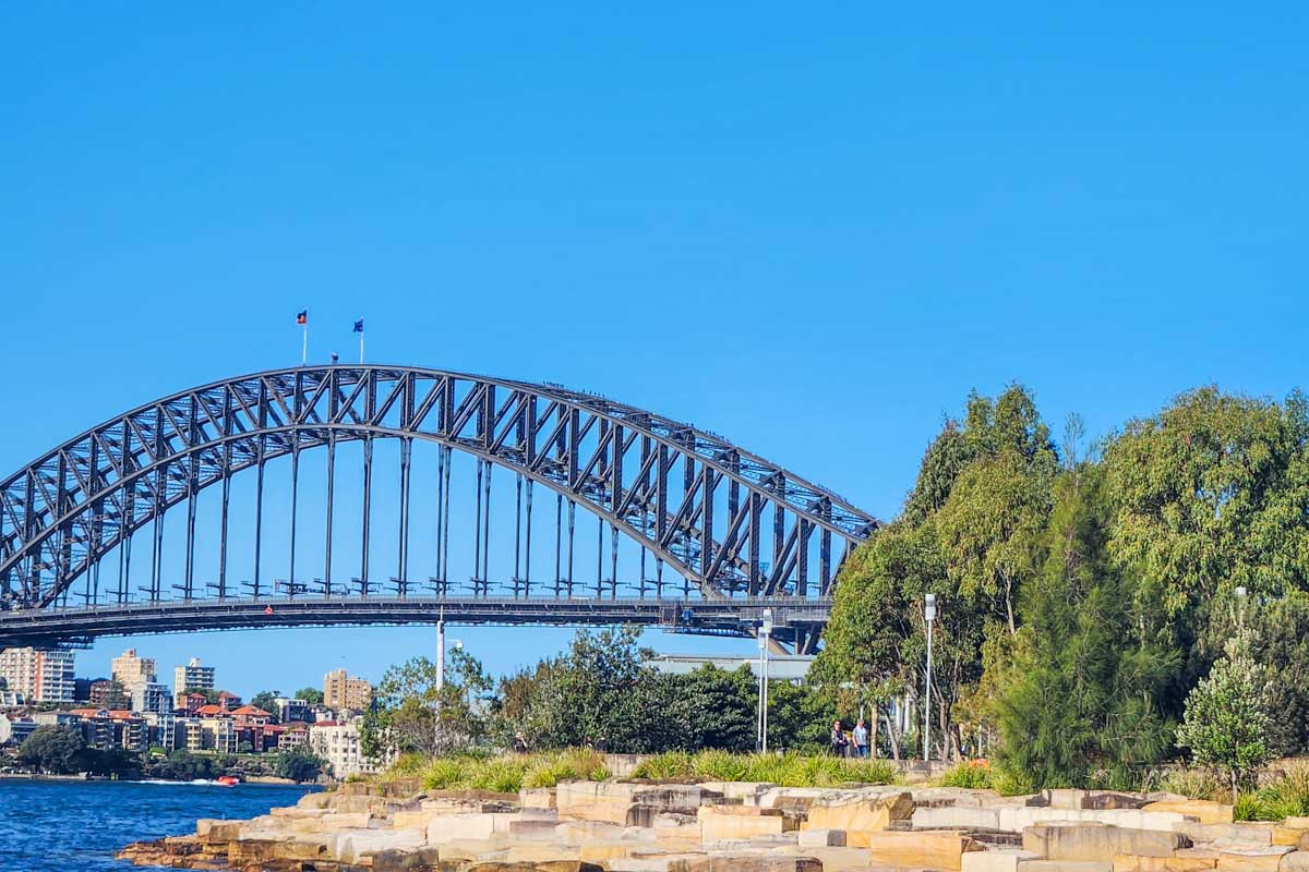 People walk along Barangaroo Reserve with the Sydney Harbour Bridge in the background